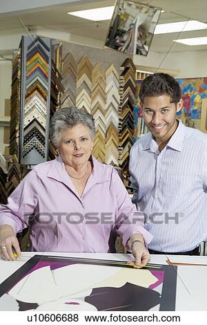 Portrait of senior female owner with customer measuring picture frame View Large Photo Image Stock Photo - Portrait of senior female owner with customer measuring picture frame. Fotosearch