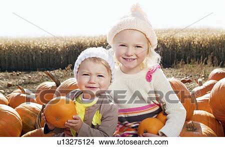 Portrait of sisters with pumpkin sitting on farm View Large Photo Image Picture - Portrait of sisters with pumpkin sitting on farm. Fotosearch