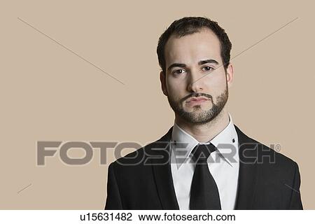 Stock Image - Portrait of young businessman with short hair and beard over colored background. Fotosearch
