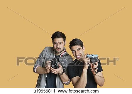 Portrait of young male friends with digital camera over colored background View Large Photo Image Stock Image - Portrait of young male friends with digital camera over colored background. Fotosearch