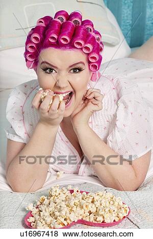 Portrait of young woman with curlers eating popcorn View Large Photo Image Stock Photo - Portrait of young woman with curlers eating popcorn. Fotosearch