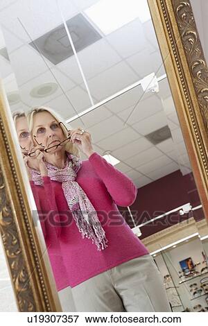 Stock Photo - Reflection of senior woman trying on glasses. Fotosearch