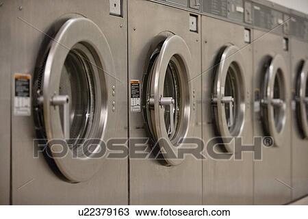 Stock Image - Row of self-service clothes dryer's door. Fotosearch