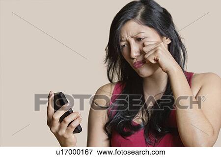 Sad young woman looking at mobile phone over colored background View Large Photo Image Stock Photo - Sad young woman looking at mobile phone over colored background. Fotosearch