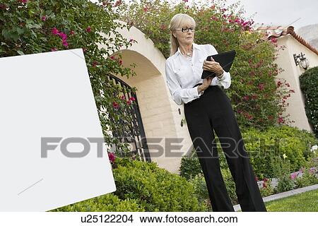 Picture - Senior female agent reading from clipboard. Fotosearch