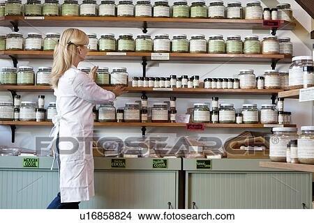 Senior female employee arranging spice jars on shelf View Large Photo Image Picture - Senior female employee arranging spice jars on shelf. Fotosearch