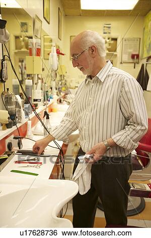 Stock Photograph - Side view of a senior barber in shop. Fotosearch
