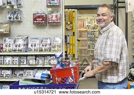 Stock Image - Side view portrait of a happy mature man with shopping cart in hardware store. Fotosearch