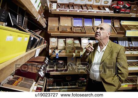 Small tobacco store owner looking at cigar boxes on display in shop View Large Photo Image Stock Photo - Small tobacco store owner looking at cigar boxes on display in shop. Fotosearch
