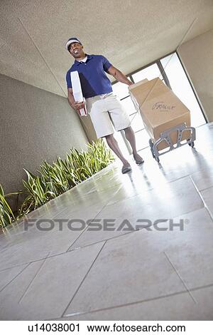 Stock Image - Tilt image of happy delivery person with packages. Fotosearch