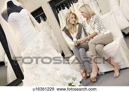 Stock Photo - Tilt shot of mother and daughter sitting with footwear in bridal store. Fotosearch