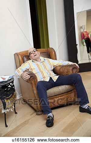 Tired senior man sitting on armchair in fashion boutique View Large Photo Image Stock Photograph - Tired senior man sitting on armchair in fashion boutique. Fotosearch