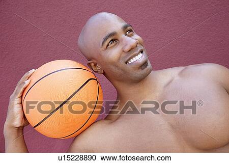 Young African American man with basketball on shoulder looking away over colored background View Large Photo Image Stock Image - Young African American man with basketball on shoulder looking away over colored background. Fotosearch