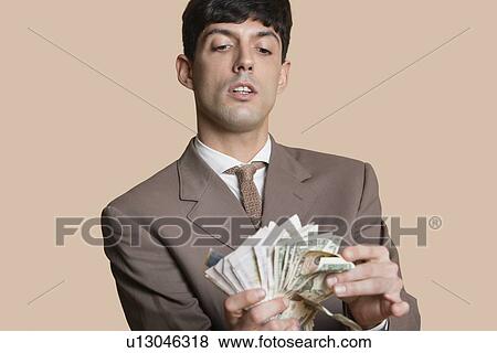 Stock Photo - Young businessman counting money over colored background. Fotosearch