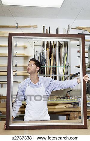 Young craftsman looking on frame's corner in workshop View Large Photo Image Stock Image - Young craftsman looking on frame's corner in workshop. Fotosearch
