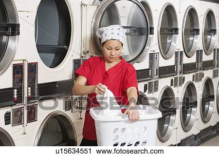 Young female employee carrying laundry basket with washing machines in background View Large Photo Image Stock Image - Young female employee carrying laundry basket with washing machines in background. Fotosearch