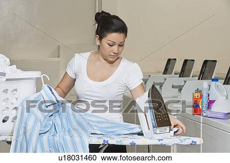 Young female employee ironing clothes in Laundromat View Large Photo Image Stock Image - Young female employee ironing clothes in Laundromat. Fotosearch