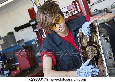 Stock Photo - Young female mechanic working on automobile machinery part in workshop. Fotosearch