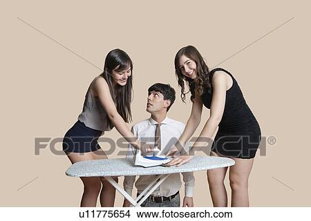 Young man looking at happy women ironing tie over colored background View Large Photo Image Picture - Young man looking at happy women ironing tie over colored background. Fotosearch