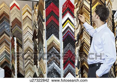 Young man looking at multi colored frames in store View Large Photo Image Stock Image - Young man looking at multi colored frames in store. Fotosearch