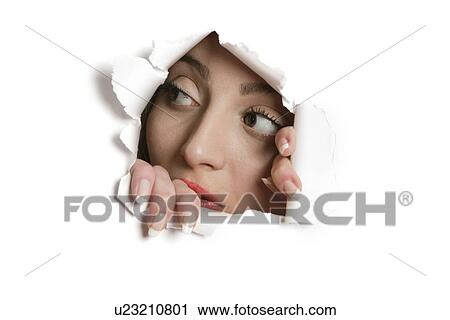 Stock Image - Young Middle eastern woman looking away from ripped paper hole. Fotosearch