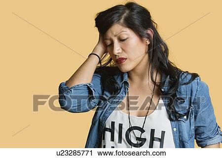 Stock Image - Young woman with hands in hair over colored background. Fotosearch