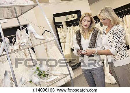 Young woman with senior mother looking at footwear in bridal store View Large Photo Image Stock Image - Young woman with senior mother looking at footwear in bridal store. Fotosearch