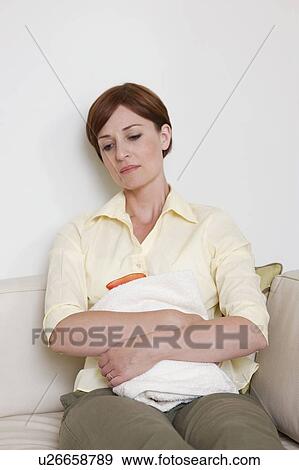 Abdominal pain. Woman holding a hot water bottle over her abdomen. View Large Photo Image Stock Photo - Abdominal pain. Woman holding a hot water bottle over her abdomen.. Fotosearch