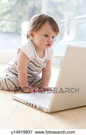 Baby playing with a laptop. 15 month old girl looking at a laptop. View Large Photo Image Stock Photo - Baby playing with a laptop. 15 month old girl looking at a laptop.. Fotosearch
