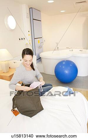 Stock Image - Birthing centre. Pregnant woman unpacking in her room at a birthing centre.. Fotosearch
