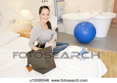 Stock Photograph - Birthing centre. Pregnant woman unpacking in her room at a birthing centre.. Fotosearch
