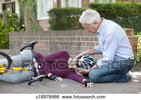 Cycling accident. Man helping a cyclist that has fallen from her bike. View Large Photo Image Stock Photograph - Cycling accident. Man helping a cyclist that has fallen from her bike.. Fotosearch