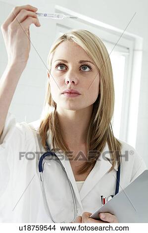 Doctor checking a thermometer. View Large Photo Image Picture - Doctor checking a thermometer.. Fotosearch