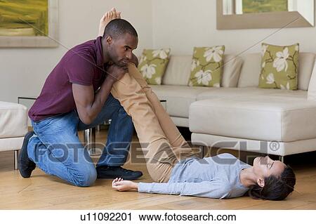 Stock Image - Fainting. Man raising the legs of a woman who has fainted.. Fotosearch