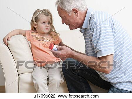Stock Image - First aid for poisoning. Man asking a young girl if she has swallowed some pills.. Fotosearch