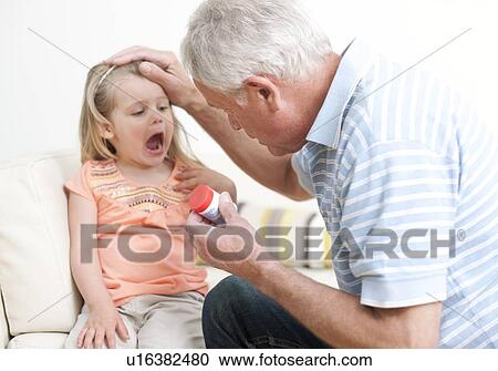 Stock Image - First aid for poisoning. Man checking a young girl's mouth for pills.. Fotosearch