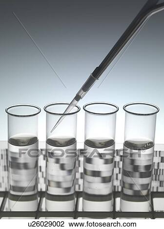 Stock Image - Genetic research. Pipetting into a test tube sitting in front of a DNA (deoxyribonucleic acid) autoradiogram.. Fotosearch