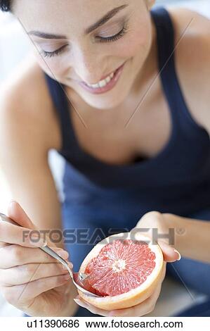 Stock Photograph - Healthy eating. Woman eating a grapefruit.. Fotosearch