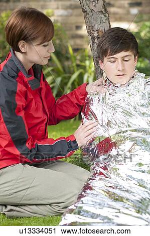 Hypothermia. Woman wrapping a boy in a foil blanket to warm him up. View Large Photo Image Stock Image - Hypothermia. Woman wrapping a boy in a foil blanket to warm him up.. Fotosearch