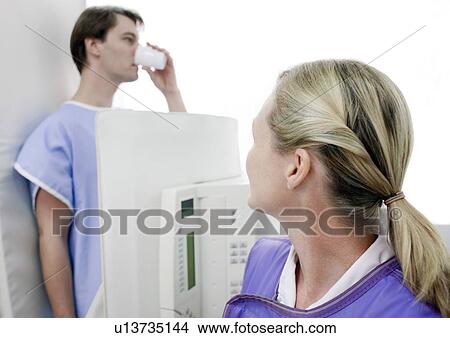 Picture - Man swallowing barium during an X-ray examination.. Fotosearch