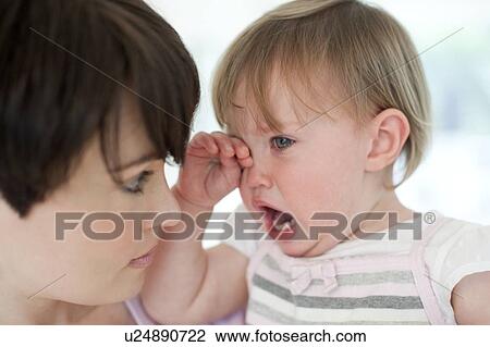Stock Image - Mother and daughter. Mother holding her tired 15 month old daughter.. Fotosearch