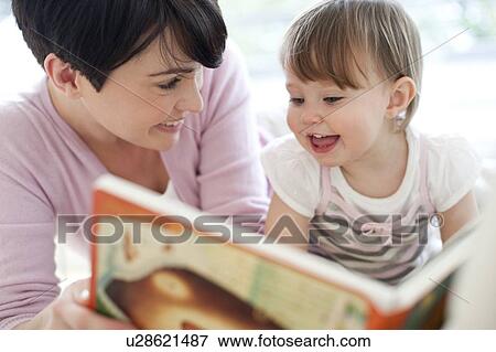 Stock Photo - Mother and daughter. Mother reading to her 15 month old daughter.. Fotosearch