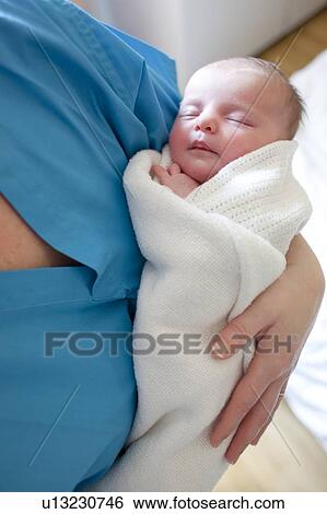 Newborn baby held by a nurse. View Large Photo Image Stock Photograph - Newborn baby held by a nurse.. Fotosearch