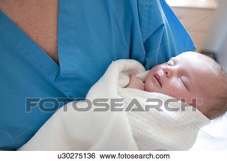 Stock Photograph - Newborn baby held by a nurse.. Fotosearch