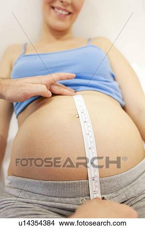 Picture - Obstetric examination. Midwife measuring a pregnant woman's abdomen at a birthing centre.. Fotosearch