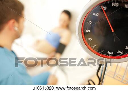 Stock Image - Obstetric examination. Midwife measuring a pregnant woman's blood pressure at a birthing centre.. Fotosearch