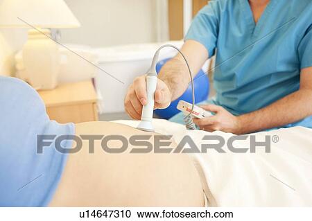 Stock Image - Obstetric examination. Midwife using a doppler monitor to listen to a foetus' heartbeat at a birthing centre.. Fotosearch