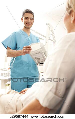 Photodynamic therapy. Dermatologist positioning a photodynamic therapy lamp over a patient. View Large Photo Image Picture - Photodynamic therapy. Dermatologist positioning a photodynamic therapy lamp over a patient.. Fotosearch