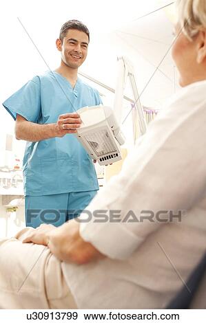 Photodynamic therapy. Dermatologist positioning a photodynamic therapy lamp over a patient. View Large Photo Image Stock Photo - Photodynamic therapy. Dermatologist positioning a photodynamic therapy lamp over a patient.. Fotosearch