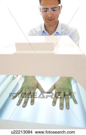 Picture - Phototherapy booth. Patient with their hands in a phototherapy box.. Fotosearch